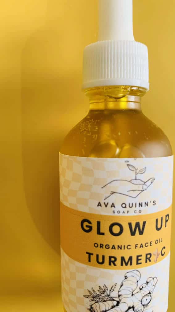 Golden Glow Turmeric Face Oil bottle with turmeric roots and carrot seeds in the background
