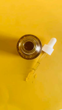 Golden Glow Turmeric Face Oil bottle with turmeric roots and carrot seeds in the background