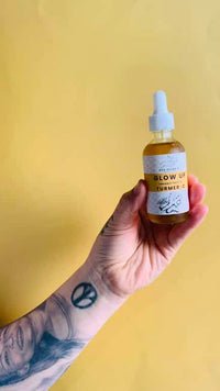 Golden Glow Turmeric Face Oil bottle with turmeric roots and carrot seeds in the background