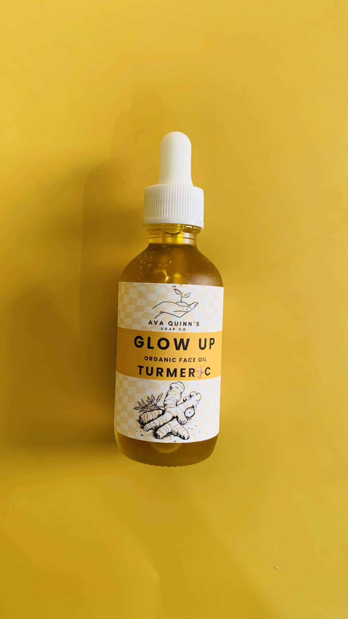 Golden Glow Turmeric Face Oil bottle with turmeric roots and carrot seeds in the background